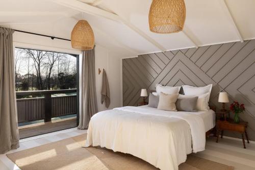 a bedroom with a white bed and a large window at Peaceful Nelson getaway - spa pool, space & views in Nelson