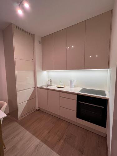 een keuken met witte kasten en een zwarte vaatwasser bij Apartament 70 Metro in Warschau