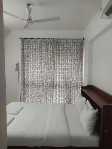 a bedroom with a white bed and a window at Pool view 1 BHK 10 min from beach in Dabolim