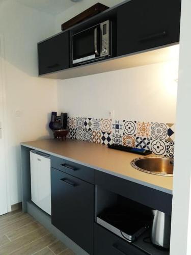 une cuisine avec un évier et un micro-ondes dans l'établissement Studio Mado proche centre ville questembert, à Questembert