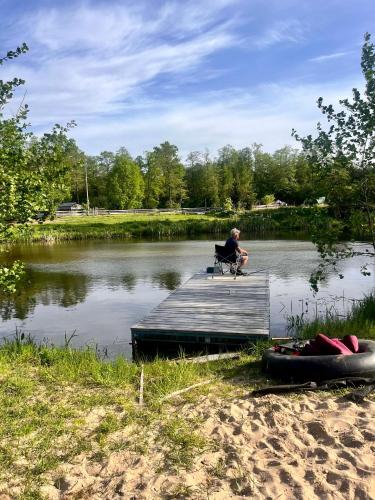 a man sitting on a chair on a dock on a lake at Apartament-samodzielne mieszkanie-Agroturystyka-puszcza kampinoska in Leoncin