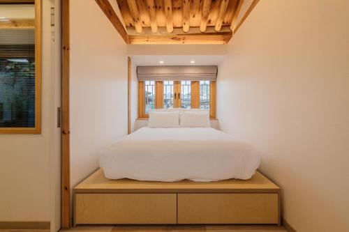 a bedroom with a white bed and a window at Luxury Hanok Seochon Stay in Seoul