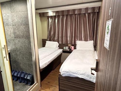 a small room with two beds and a shower at 香港星星旅馆 2202 Guesthouse in Hong Kong