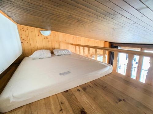 Ce lit se trouve dans un chalet doté d'un plafond en bois. dans l'établissement Résidence Sefcotel - Studio mezzanine·Proche des pistes et commerces MAE-0834, à Tignes
