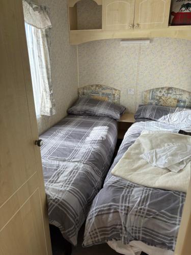 two beds in a small room with a window at 46 Newport Caravan Park Award Shortlisted Family Caravan in Hemsby