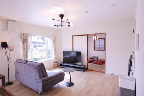 a living room with a couch and a television at 81 Guest House -ANKI- in Azagawa