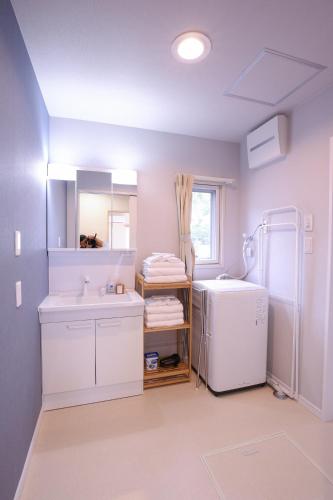 a white bathroom with a sink and a refrigerator at 81 Guest House -ANKI- in Azagawa