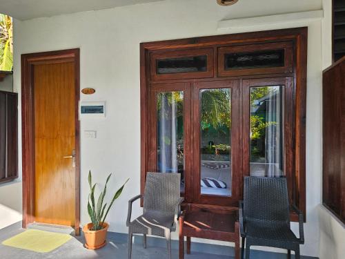 a room with two chairs and a wooden door at Garden Rooms by Lagoon View in Bodufolhudhoo