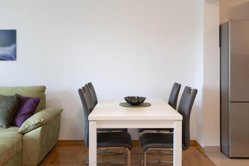- une table à manger blanche avec des chaises et un canapé dans l'établissement Bright 1BDR with Balcony & Parking, à Zagreb