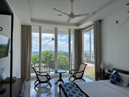 a bedroom with a bed and chairs and a large window at The Cloud Hanthana, Kandy in Kandy