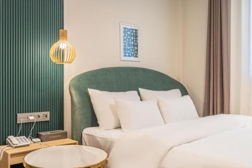 a bedroom with a large bed with a green headboard at Browndot hotel Gimhae cityhall in Gimhae