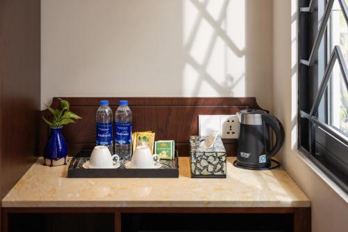 a table with a coffee maker and bottles of water at Hanoi Calista Hotel & Spa in Hanoi