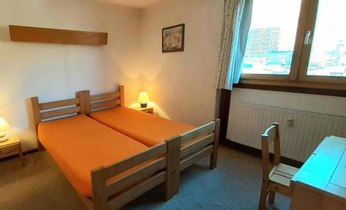 une chambre avec un lit avec un couvre-lit orange dans l'établissement Résidence Le Mustag - Résidence LE MUSTAG N°R4 MAE-1431, à La Plagne Tarentaise