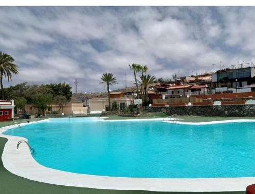 a large blue swimming pool with buildings in the background at Maspalomas Pasito in Pasito Blanco