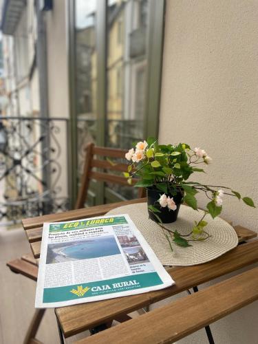 a table with a newspaper and a vase of flowers at Hotel Puerto de Luarca in Luarca