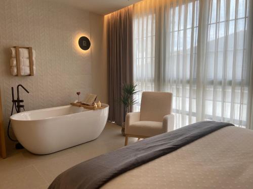 a bathroom with a tub and a chair and a bed at Hotel Puerto de Luarca in Luarca