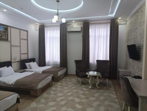 a hotel room with two beds and a table at GRAND SARBON HOTEL in Qarshi