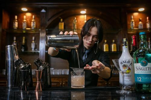 a woman bartender making a drink at a bar at TrangTrang Luxury Hotel in Hanoi