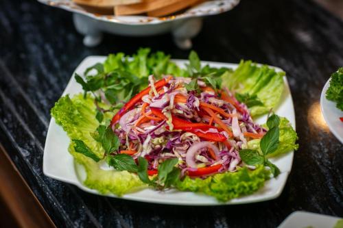 a salad on a white plate on a table at TrangTrang Luxury Hotel in Hanoi