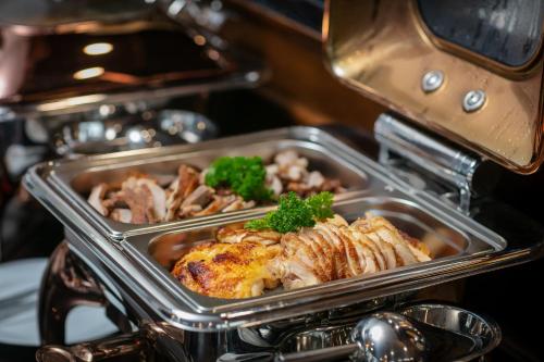 a tray of food in an oven with chicken and meat at TrangTrang Luxury Hotel in Hanoi