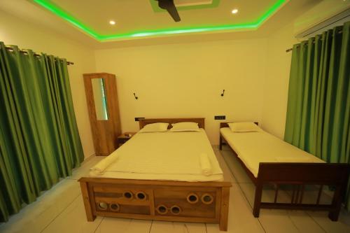 a bedroom with two beds and green curtains at Prakruthi Residency Munroeisland in Munroe Island