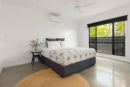 a white bedroom with a bed and a window at Eleven Watson Guesthouse in Mossman