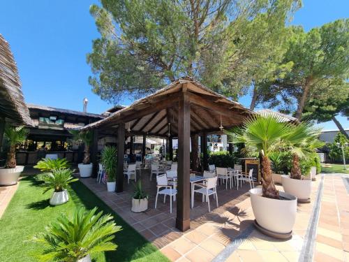a pavilion with tables and chairs and palm trees at Hotel Boutique Mirasierra in Villacañas