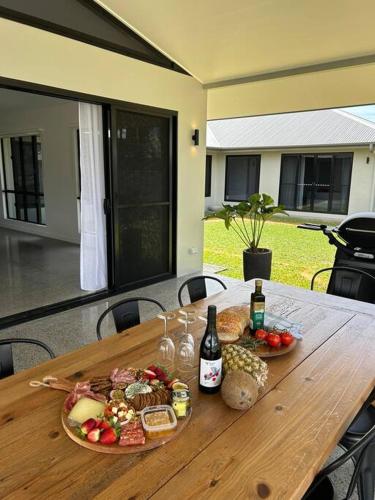 a wooden table with plates of food and bottles of wine at Eleven Watson Guesthouse in Mossman