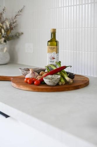 a bottle of wine and vegetables on a cutting board at Eleven Watson Guesthouse in Mossman