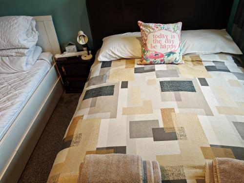 a bed with a quilt on it with a pillow on it at king size bed -Room near Bournemouth Hospital shared bathroom in Bournemouth