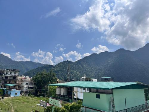 a building with a green roof with mountains in the background at The GreenView HomeStay in Rishīkesh