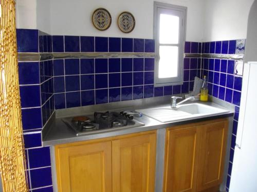 une cuisine avec un évier et du carrelage bleu au mur dans l'établissement La maison du pêcheur à Porticciolo Cap-Corse, à Portocciolo