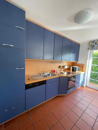 a kitchen with blue cabinets and a sink at Twenge Retreat - Haus Nähe Stadt und Flughafen mit Garten, 3 Zimmer, TV, Küche, Bad und Netflix in Altenhorst