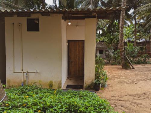 a small house with a wooden door on it at Sunset Cafe Beach Stay in Gokarna