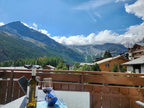 a bottle of wine on a table with a view of mountains at Hotel Etoile & Alpenperle Residences in Saas-Fee