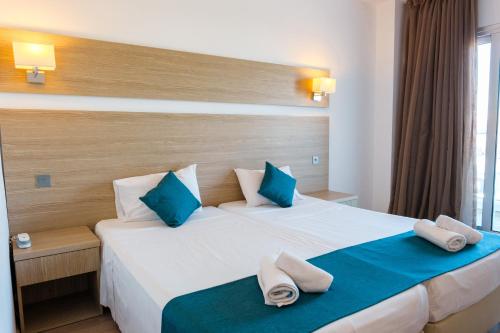 a hotel room with a large bed with blue pillows at Kapetanios Bay Hotel Protaras in Protaras