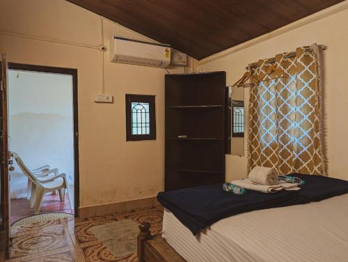 a bedroom with a bed and a chair and a window at Sunset Cafe Beach Stay in Gokarna