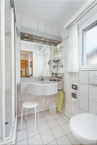 a white bathroom with a sink and a toilet at Hotel Etoile in Saas-Fee