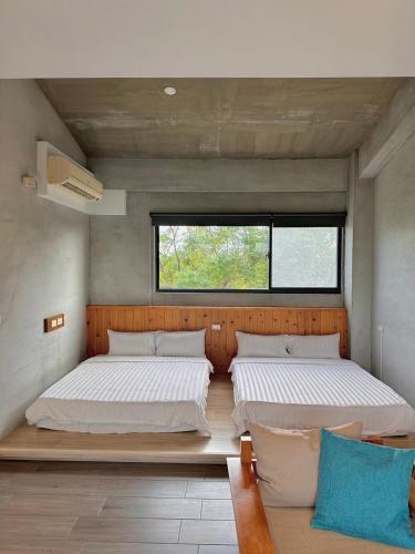 two beds in a room with a window and a couch at Lin's Forest in Hengchun