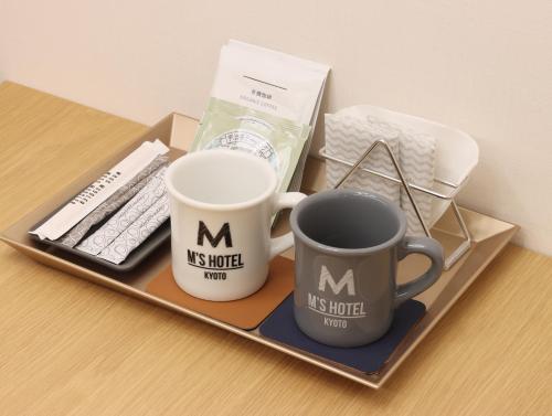 a tray with two m cups and a remote control at HOTEL Tomiya with M's in Kyoto