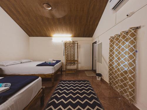 a bedroom with two beds and a wooden ceiling at Sunset Cafe Beach Stay in Gokarna