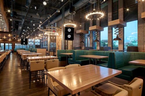 a restaurant with wooden tables and green booths at Sandman Signature Plano-Frisco Hotel in Plano