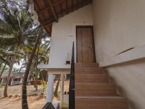 a stairway leading to a house with a wooden door at Sunset Cafe Beach Stay in Gokarna