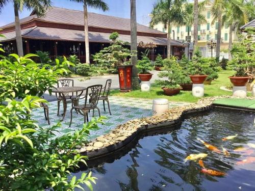 a koi pond in a garden with a table and chairs at The Mira Boutique Hotel in Thu Dau Mot