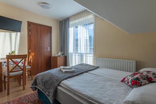 een slaapkamer met een bed, een stoel en een raam bij Tylicki Zdrój in Tylicz