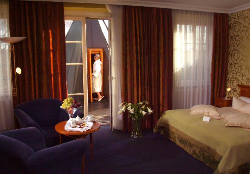 a hotel room with a bed and a woman looking out the window at Hotel BEI SCHUMANN in Kirschau