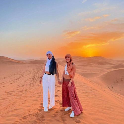 a man and a woman standing in the desert at Merzouga Horizon Luxury Camp in Merzouga