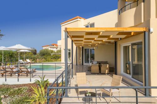 a house with a deck with chairs and a pool at AéNaos Luxury Villa with Pool in Galatas in Galatás