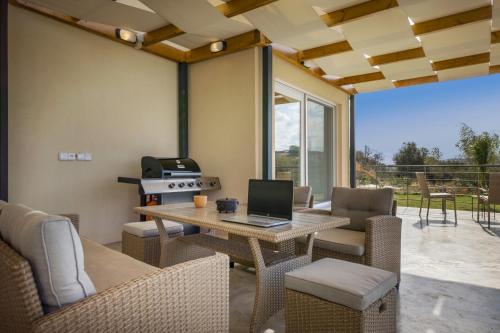 a patio with a table with a laptop on it at AéNaos Luxury Villa with Pool in Galatas in Galatás