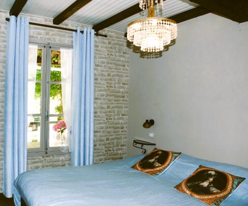 une chambre avec un lit, une fenêtre et un lustre dans l'établissement Gite Le Petit Bonheur, à Soturac